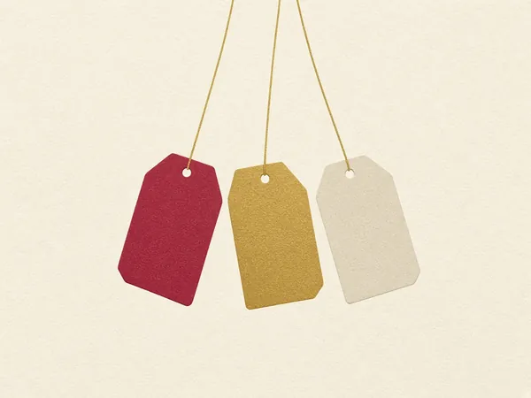 Three blank gift tags in cranberry, gold and cream hanging from gold string
